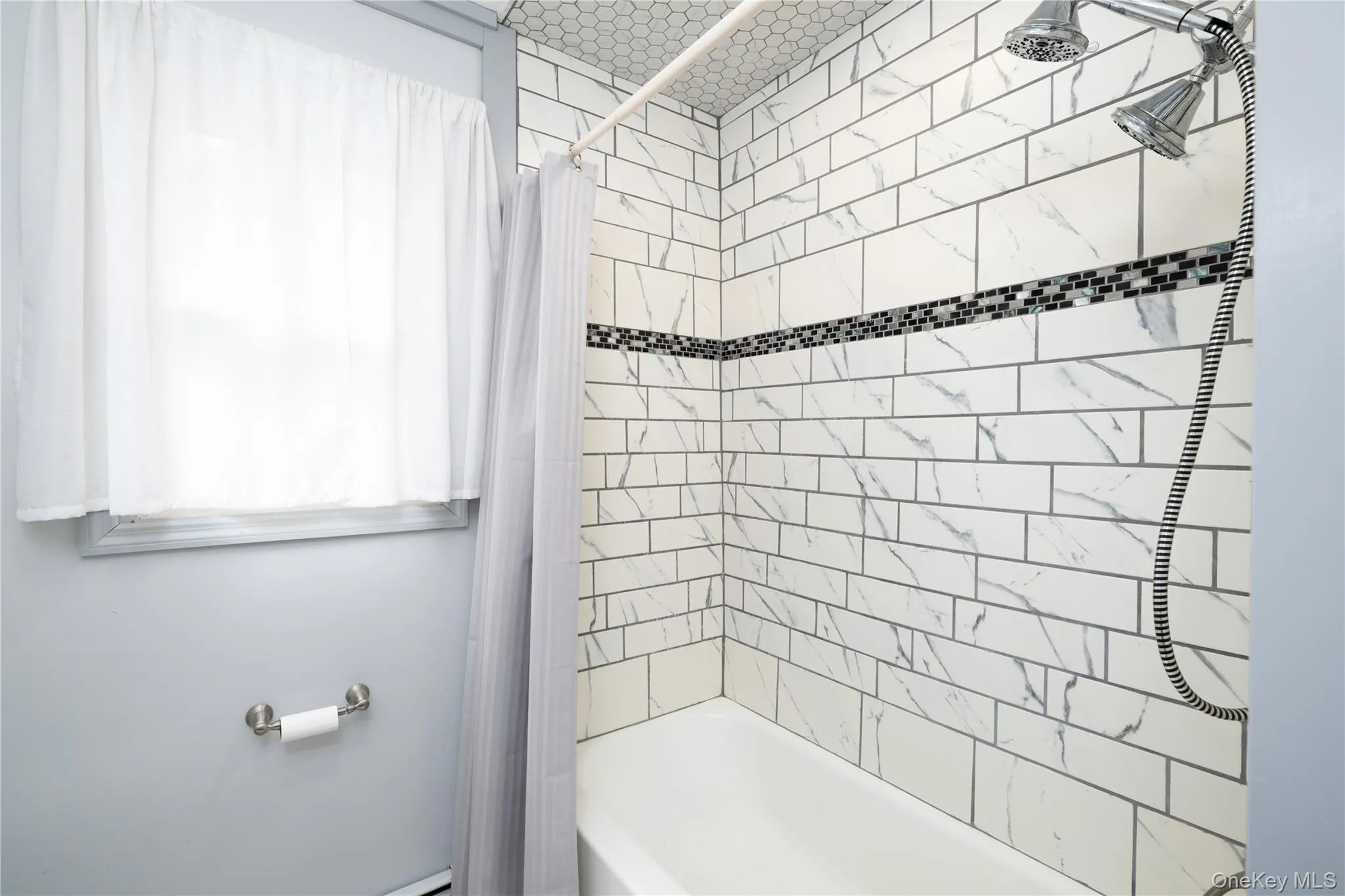 White subway tile shower surround with black mosaic accent band White subway tile shower surround with black mosaic accent band