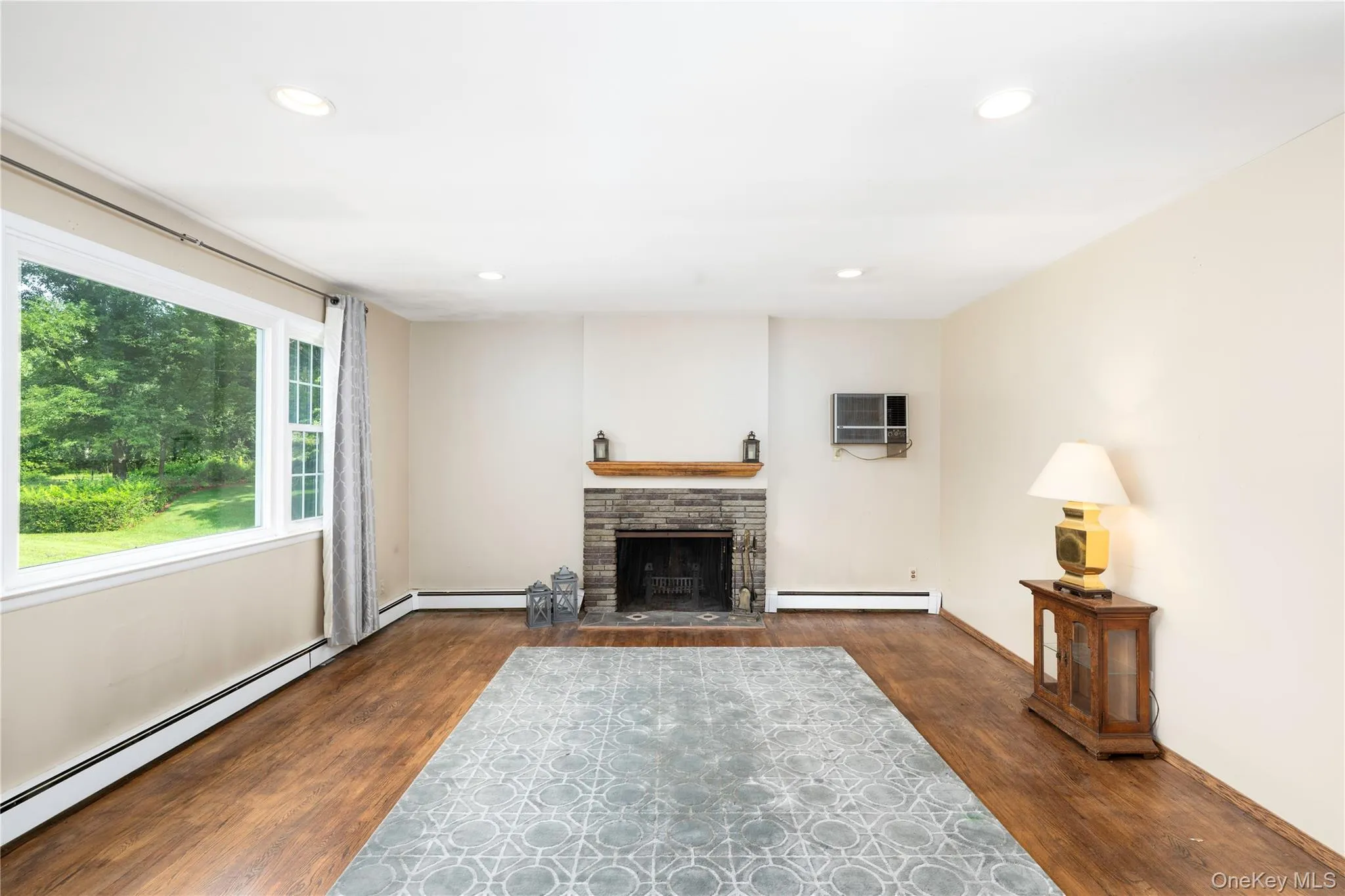 Spacious interior with hardwood flooring, a stone fireplace with a wood mantle, and recessed lighting Spacious interior with hardwood flooring, a stone fireplace with a wood mantle, and recessed lighting