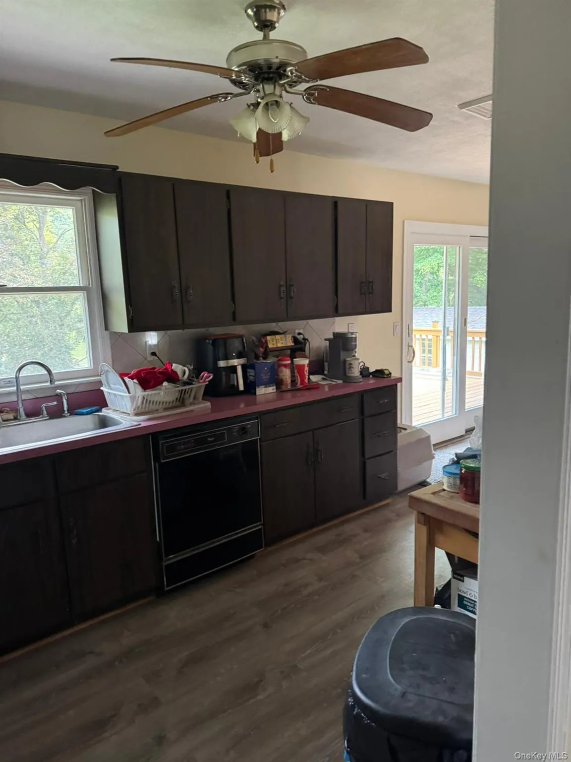 Kitchen featuring a ceiling fan, dishwasher, dark wood-style flooring, and dark brown cabinetry Kitchen featuring a ceiling fan, dishwasher, dark wood-style flooring, and dark brown cabinetry