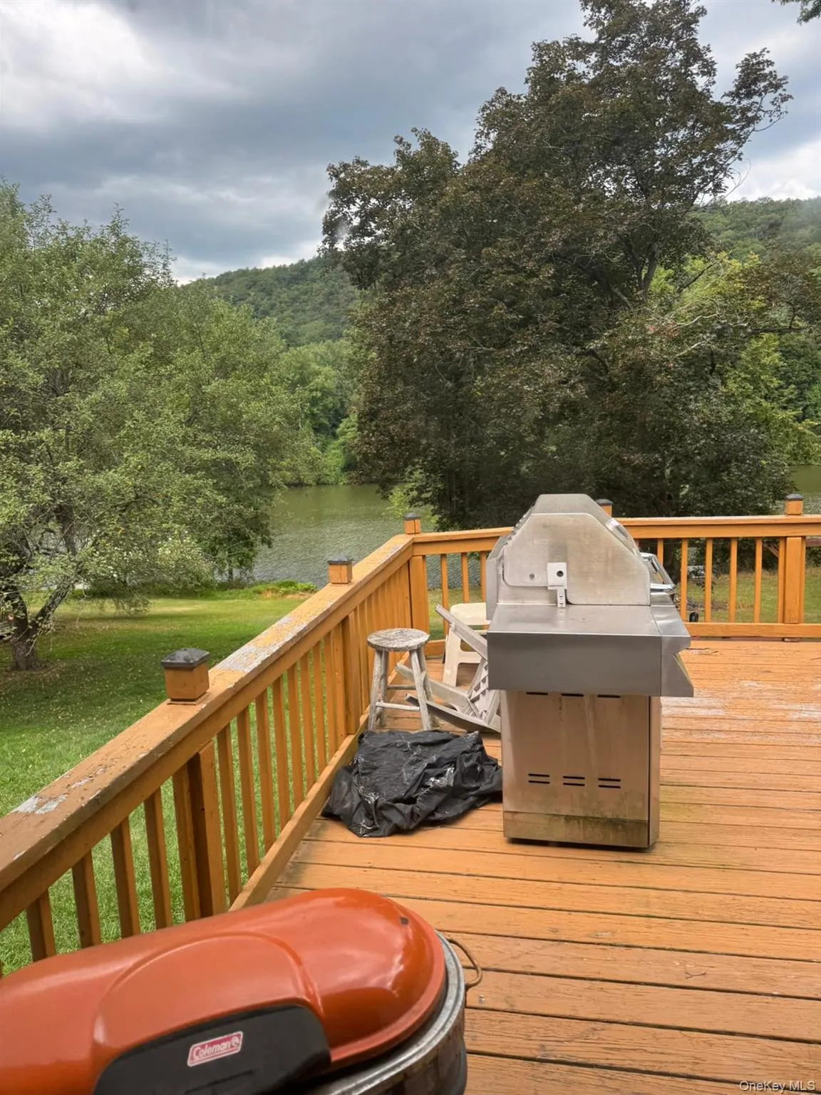 Wooden deck featuring area for grilling, a wooded view, a yard, and a water view Wooden deck featuring area for grilling, a wooded view, a yard, and a water view
