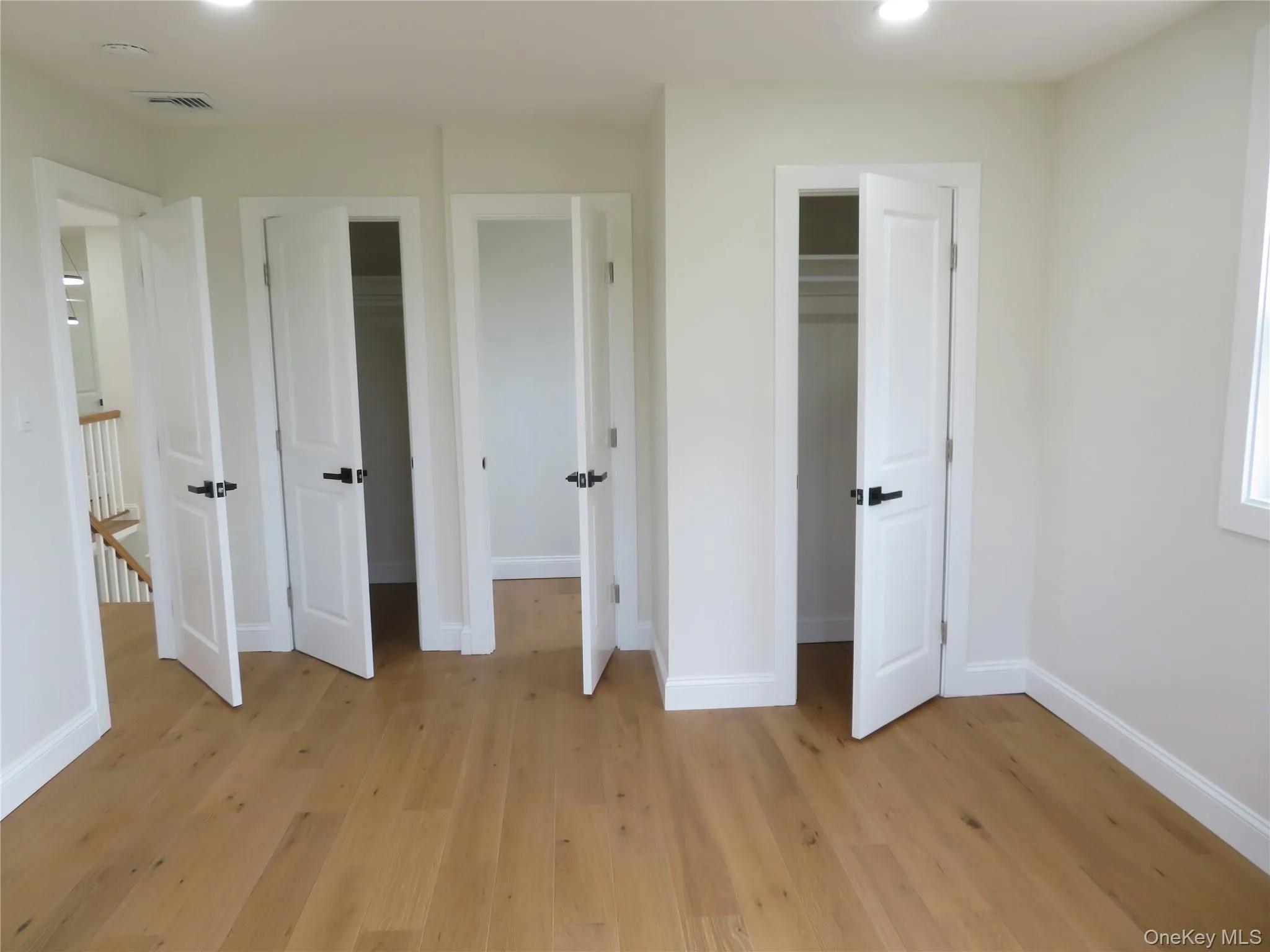 Wood-finish flooring, white paneled doors, black door hardware, white trim, and recessed lighting Wood-finish flooring, white paneled doors, black door hardware, white trim, and recessed lighting
