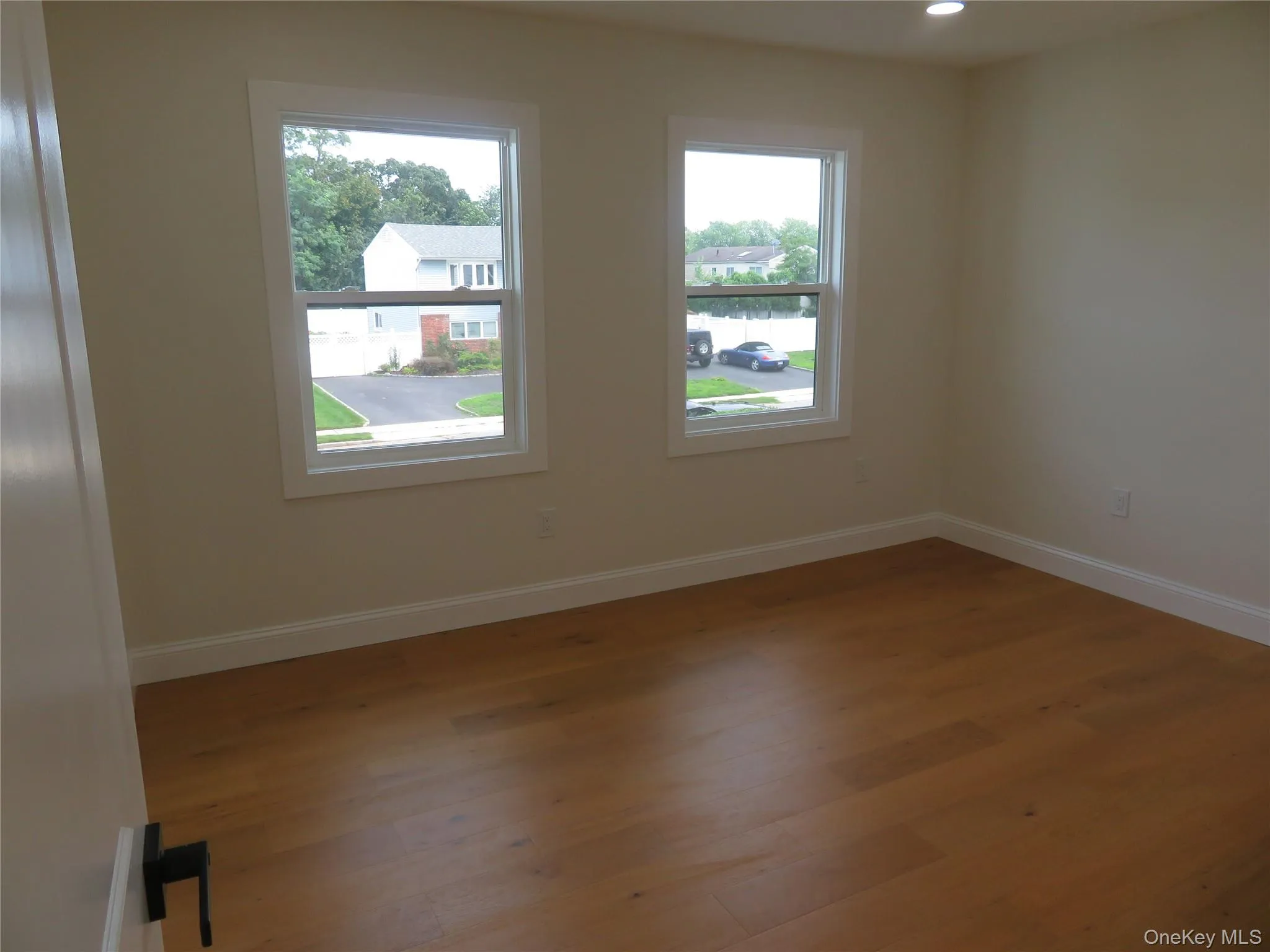 Light-colored walls, wood-finish flooring, two windows with white trim, and recessed lighting Light-colored walls, wood-finish flooring, two windows with white trim, and recessed lighting