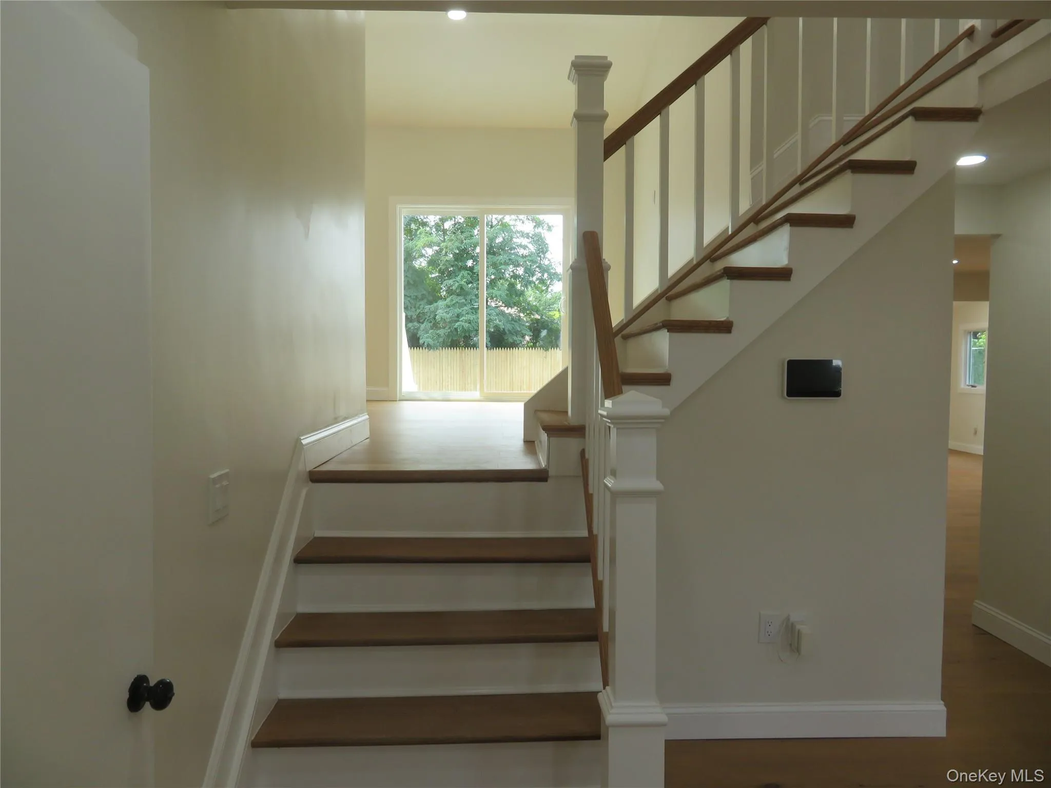 Staircase to Living room with wood treads and white risers, white newel posts, and wood handrails Staircase to Living room with wood treads and white risers, white newel posts, and wood handrails