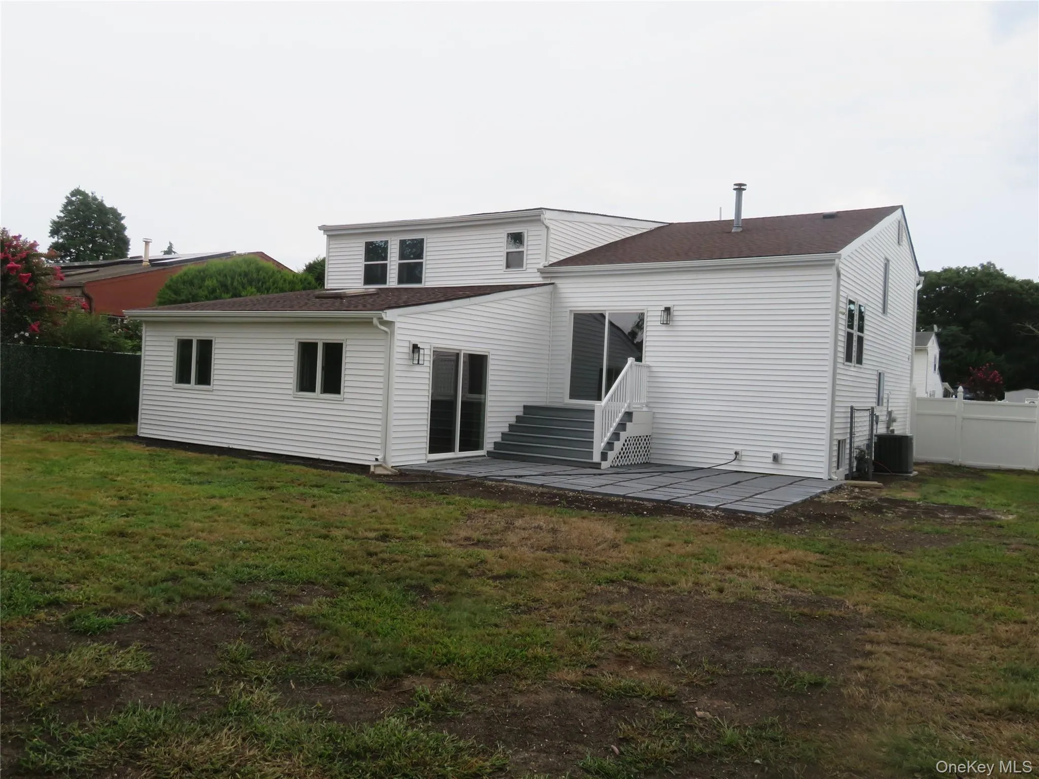 Rear exterior featuring white siding, a multi-level deck, dark shingle roof, and a privacy fence Rear exterior featuring white siding, a multi-level deck, dark shingle roof, and a privacy fence