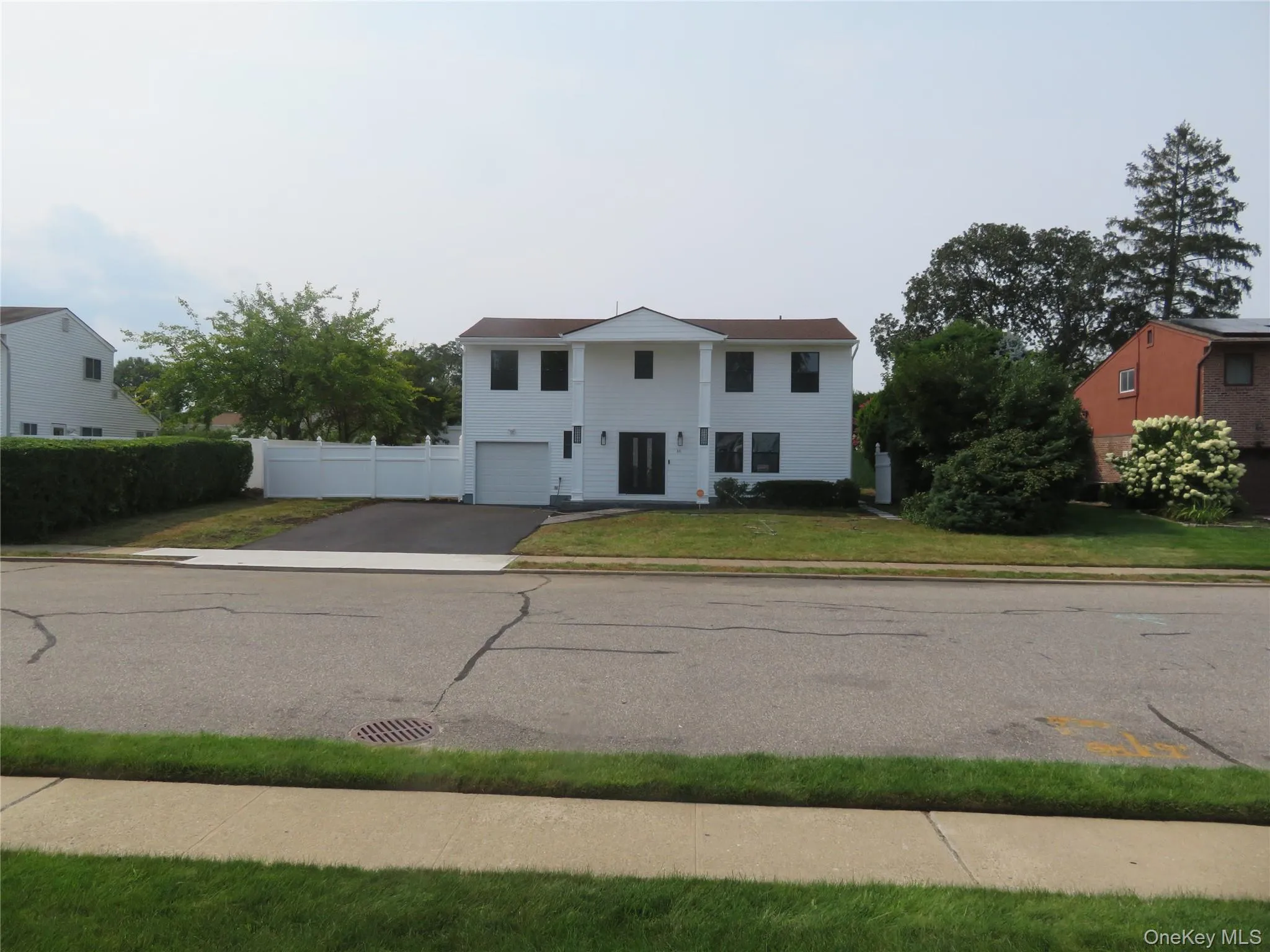 Two-story residence with a white exterior, attached garage, and a paved driveway Two-story residence with a white exterior, attached garage, and a paved driveway