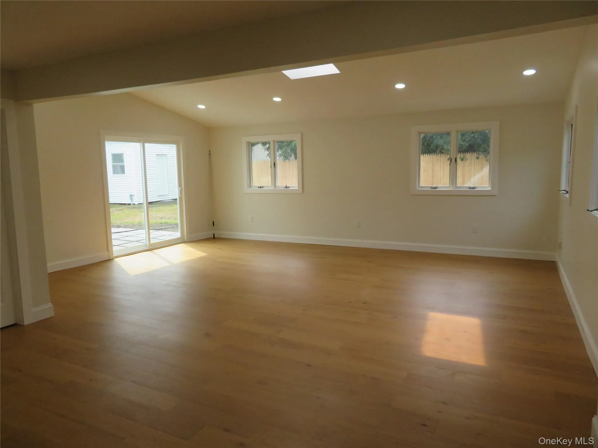 Wood-finish flooring, recessed lighting, and a vaulted ceiling with a skylight Wood-finish flooring, recessed lighting, and a vaulted ceiling with a skylight