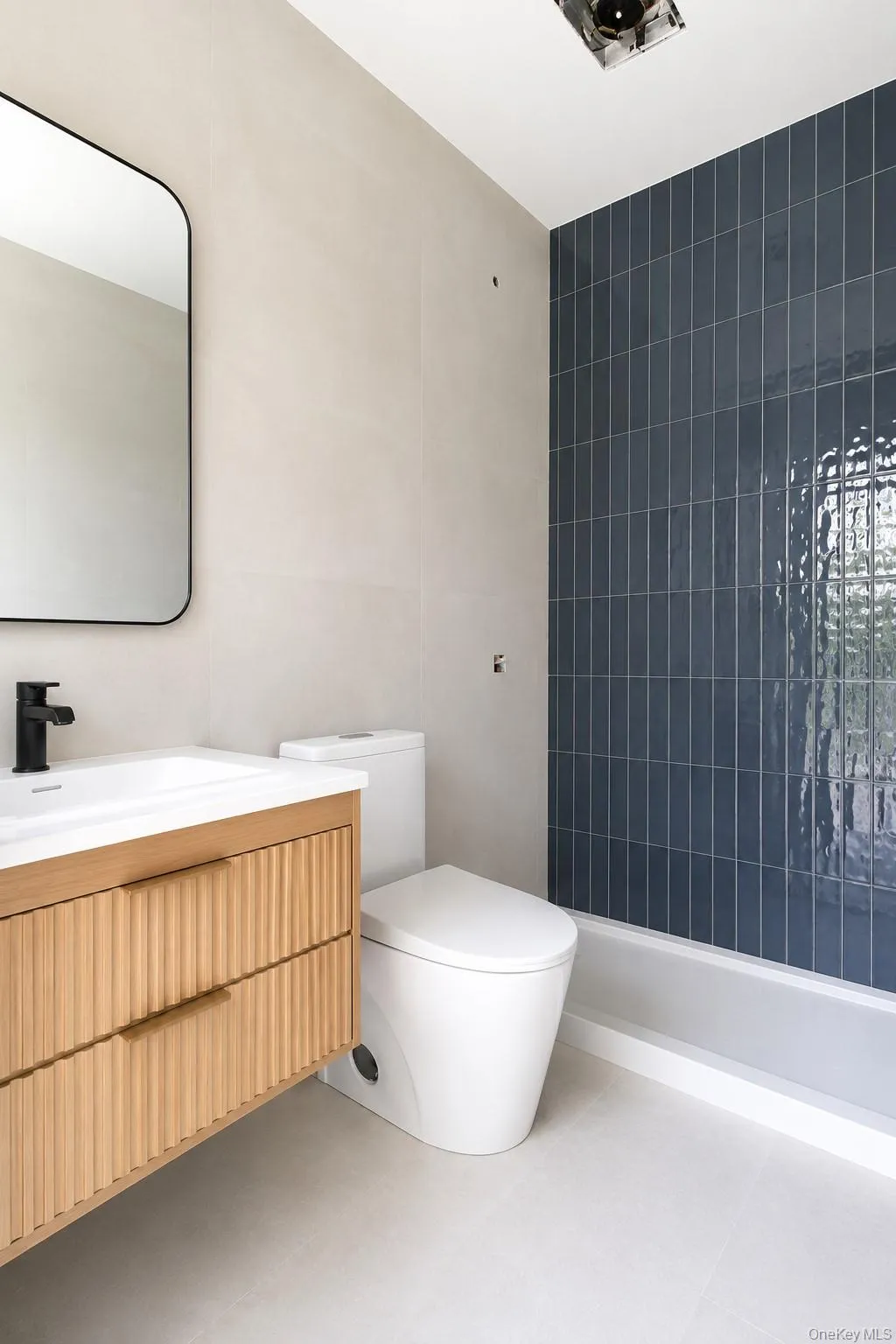 Floating wood-finish vanity with fluted drawer fronts, a rectangular undermount sink, and a matte black faucet Floating wood-finish vanity with fluted drawer fronts, a rectangular undermount sink, and a matte black faucet