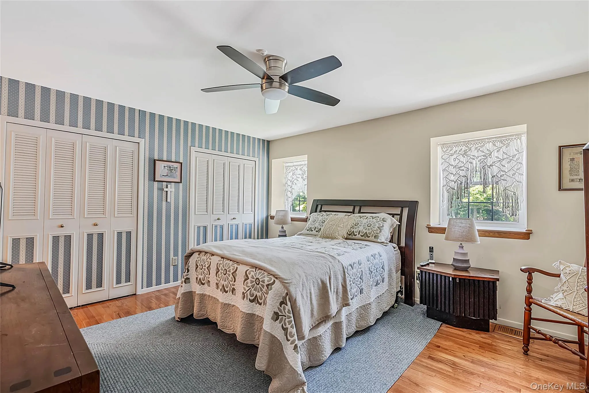Wood-finish flooring, ceiling fan with integrated lighting, and dual windows providing natural light Wood-finish flooring, ceiling fan with integrated lighting, and dual windows providing natural light