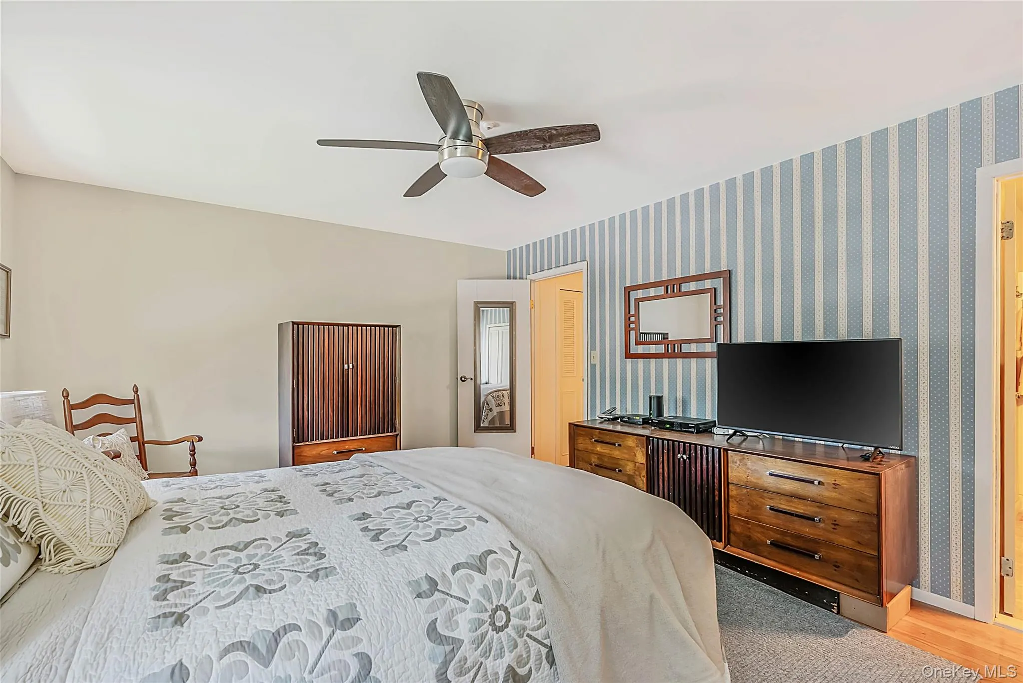 Angled ceiling with a ceiling fan, light-toned wall paint, and a striped accent wall Angled ceiling with a ceiling fan, light-toned wall paint, and a striped accent wall