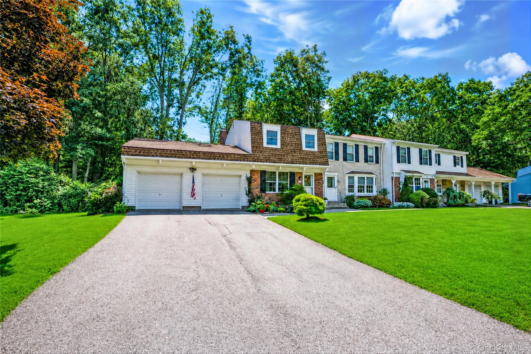 Two-story residence with a two-car garage, dormer windows, and a brick facade accent Two-story residence with a two-car garage, dormer windows, and a brick facade accent