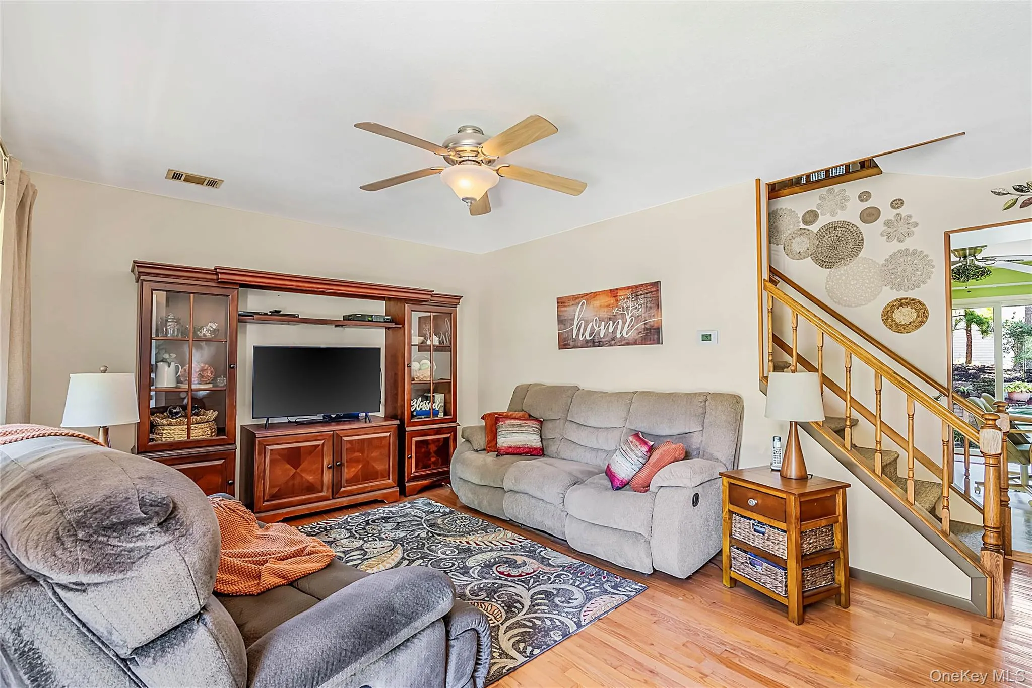 Hardwood flooring throughout, ceiling fan with integrated lighting, and a staircase with wood banister Hardwood flooring throughout, ceiling fan with integrated lighting, and a staircase with wood banister