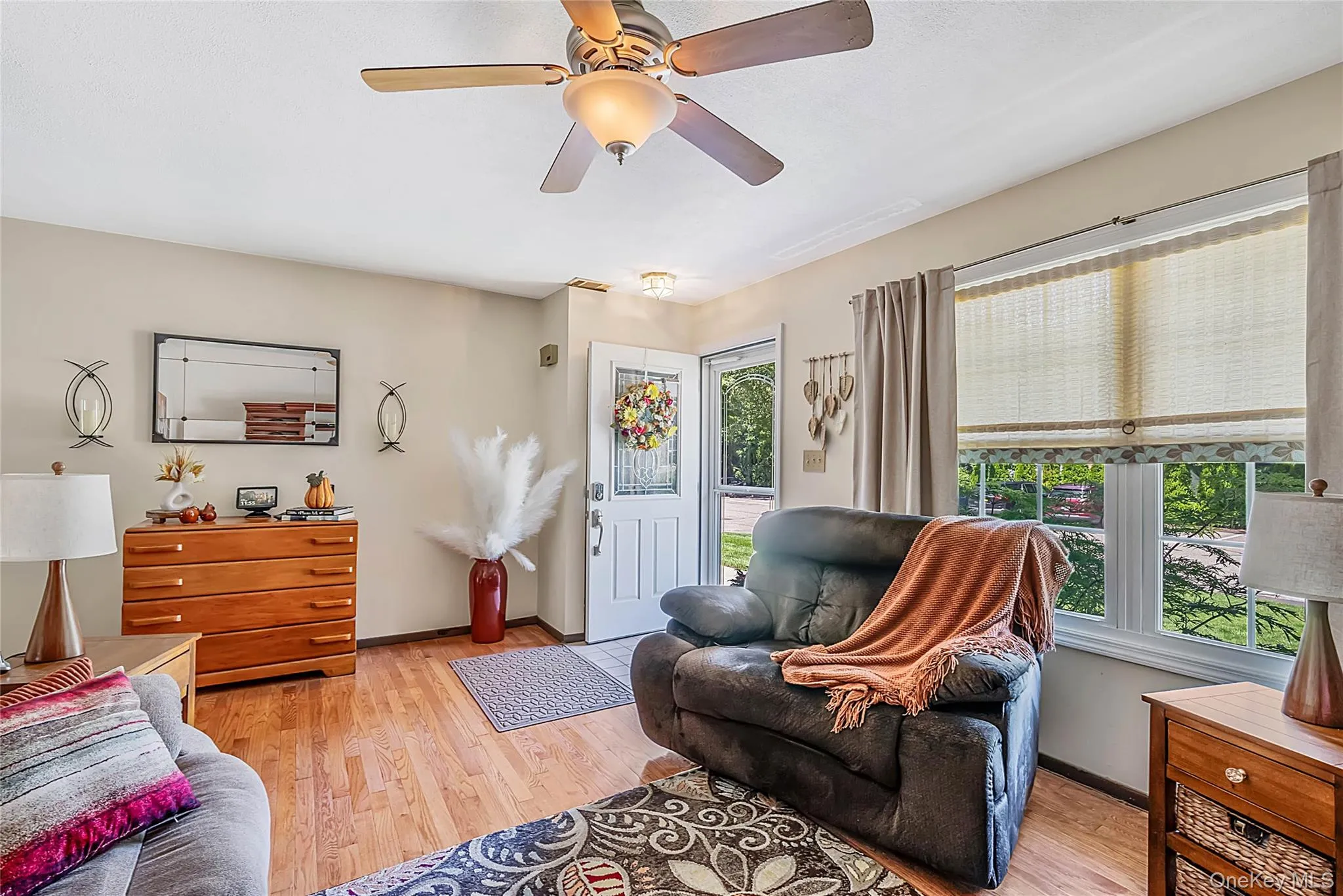 Hardwood-finish flooring, ceiling fan with integrated lighting, white interior door, large window, and neutral wall tones Hardwood-finish flooring, ceiling fan with integrated lighting, white interior door, large window, and neutral wall tones