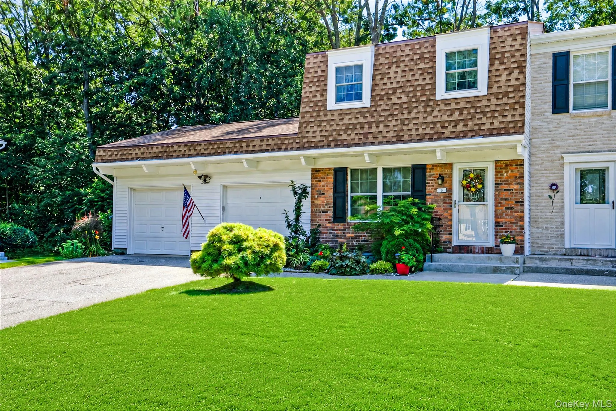 Brick and siding exterior with a two-car garage, dormer windows, and established landscaping Brick and siding exterior with a two-car garage, dormer windows, and established landscaping