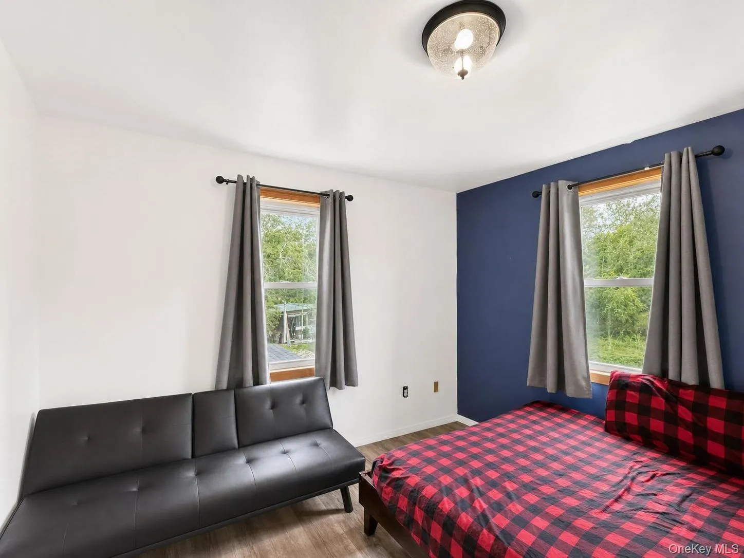 Two windows with wood trim, a ceiling-mounted light fixture, and wood-finish flooring Two windows with wood trim, a ceiling-mounted light fixture, and wood-finish flooring