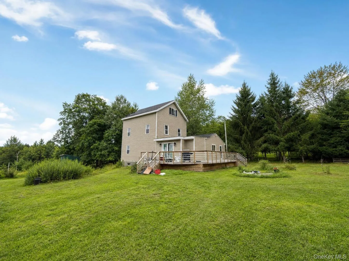 Expansive green lawn, multi-level wood deck, white patio door, light-colored siding, mature trees Expansive green lawn, multi-level wood deck, white patio door, light-colored siding, mature trees