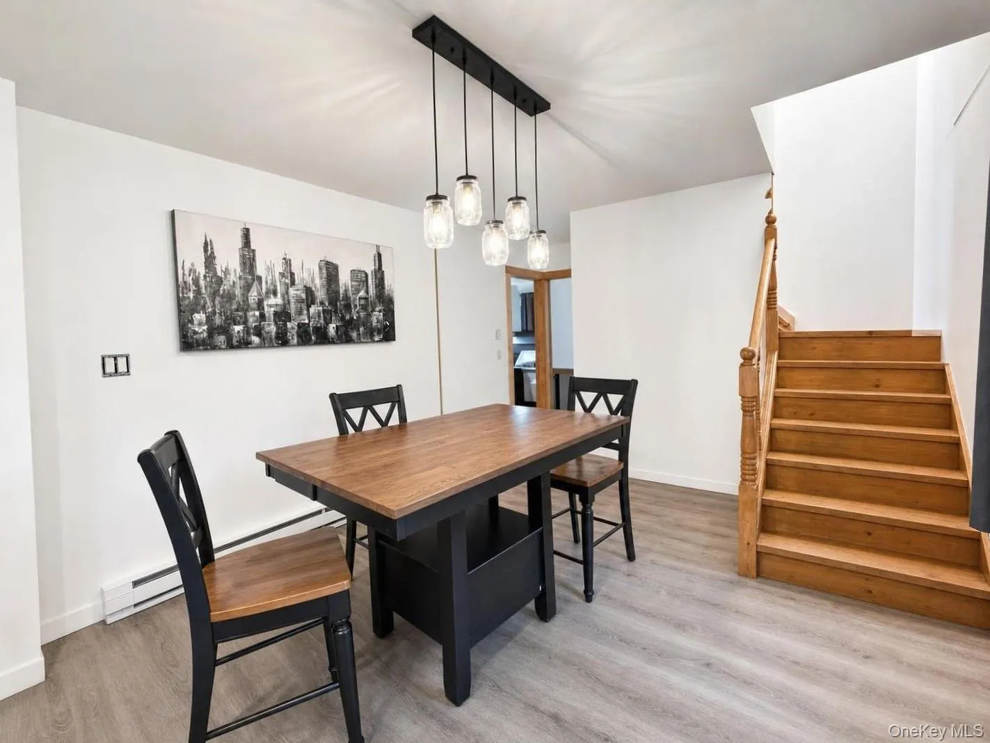 Light wood-finish flooring, wood staircase with banister, and contemporary pendant lighting fixture Light wood-finish flooring, wood staircase with banister, and contemporary pendant lighting fixture