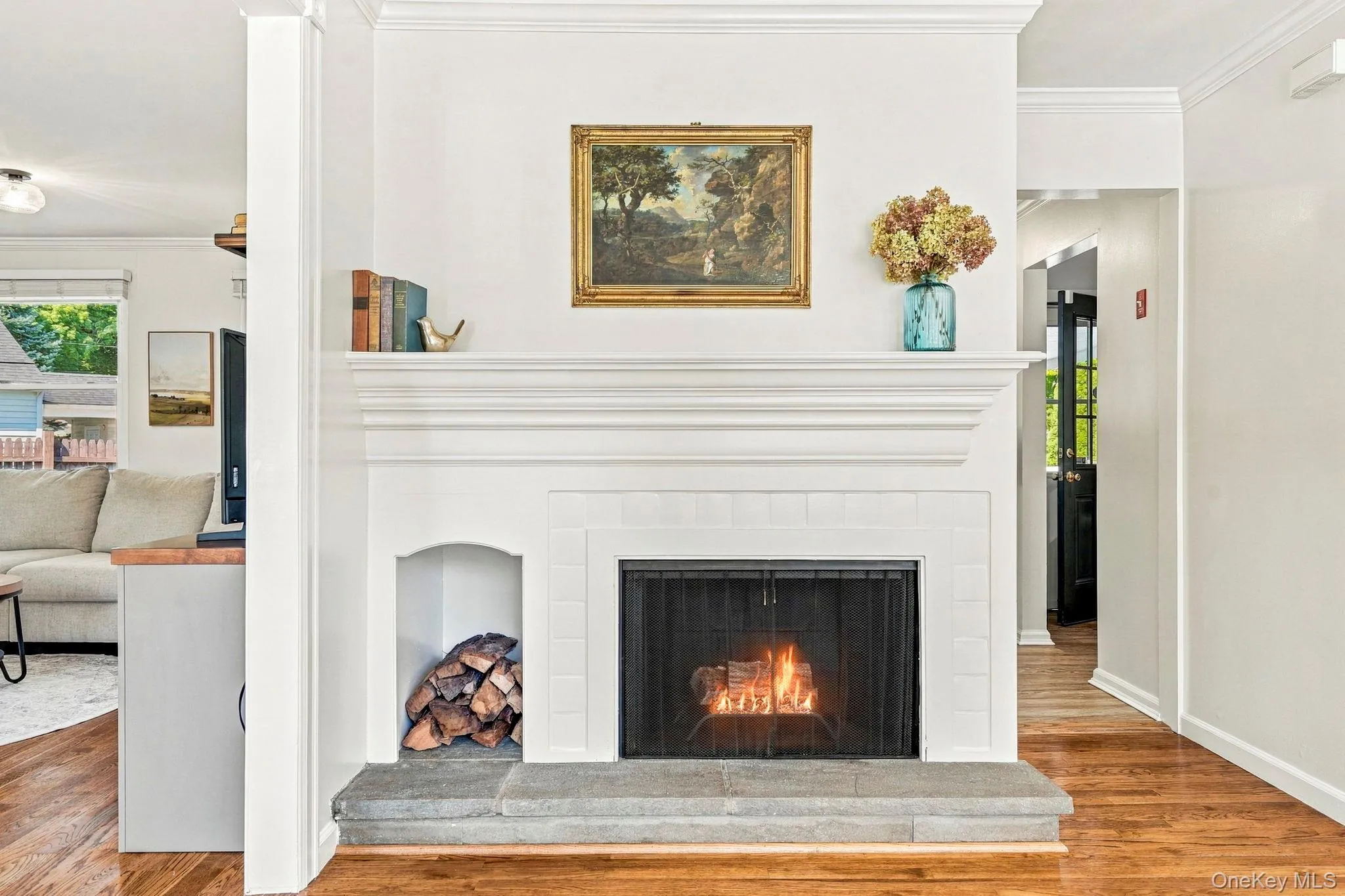 Wood burning fireplace with a detailed mantel, tiled surround, integrated log storage, and a stone hearth Wood burning fireplace with a detailed mantel, tiled surround, integrated log storage, and a stone hearth