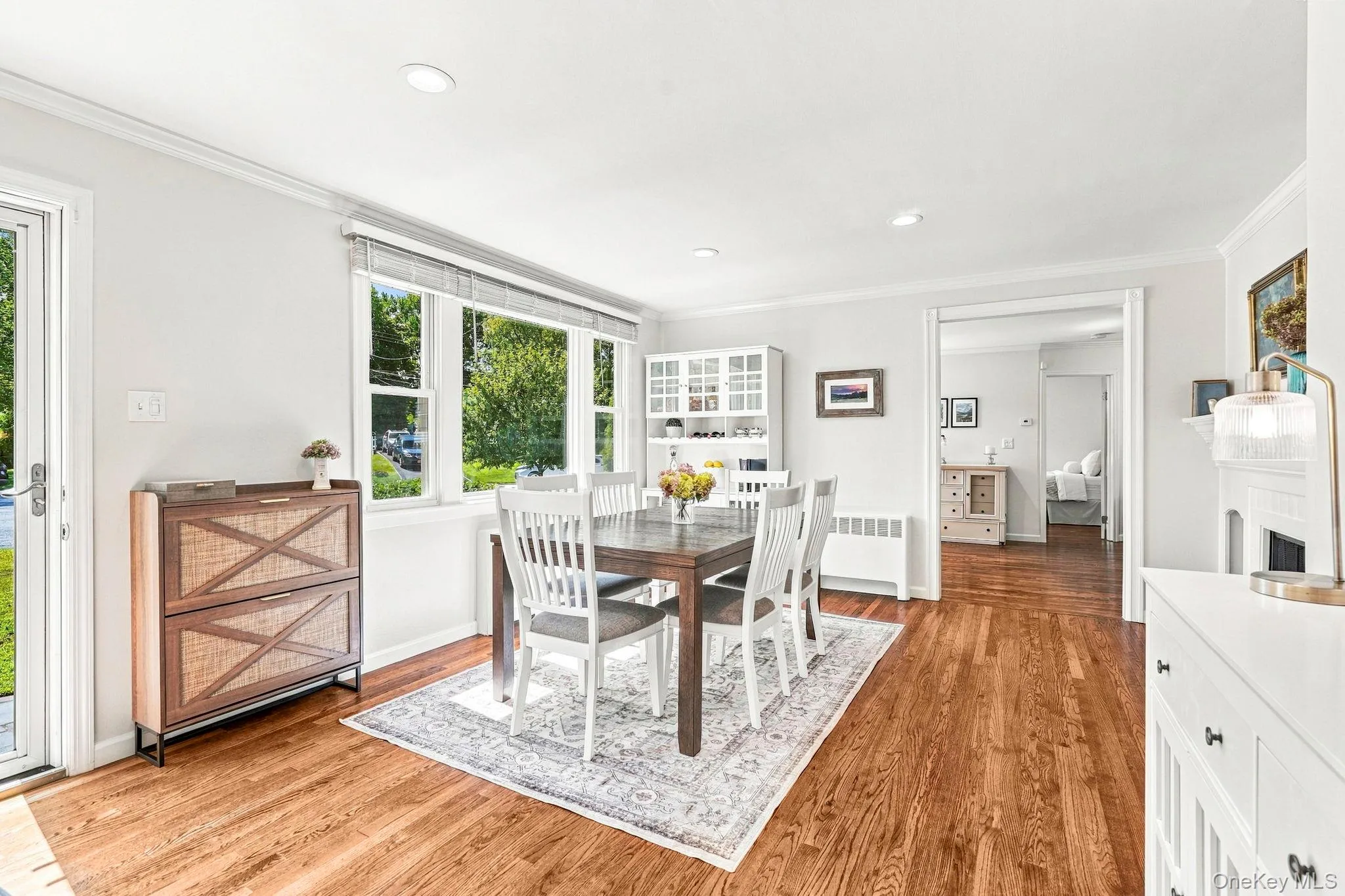 Hardwood flooring, recessed lighting, white wall paneling, built-in display cabinetry, and a white mantel Hardwood flooring, recessed lighting, white wall paneling, built-in display cabinetry, and a white mantel