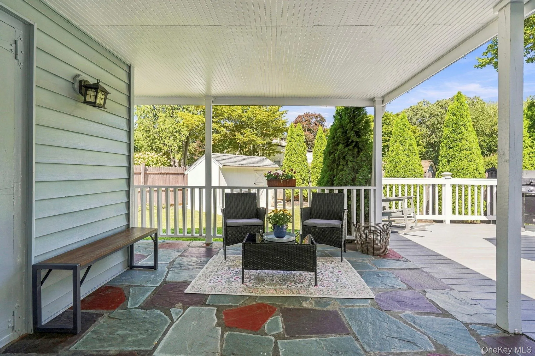 Covered patio featuring a colorful flagstone floor, white railing, and exterior wall siding Covered patio featuring a colorful flagstone floor, white railing, and exterior wall siding