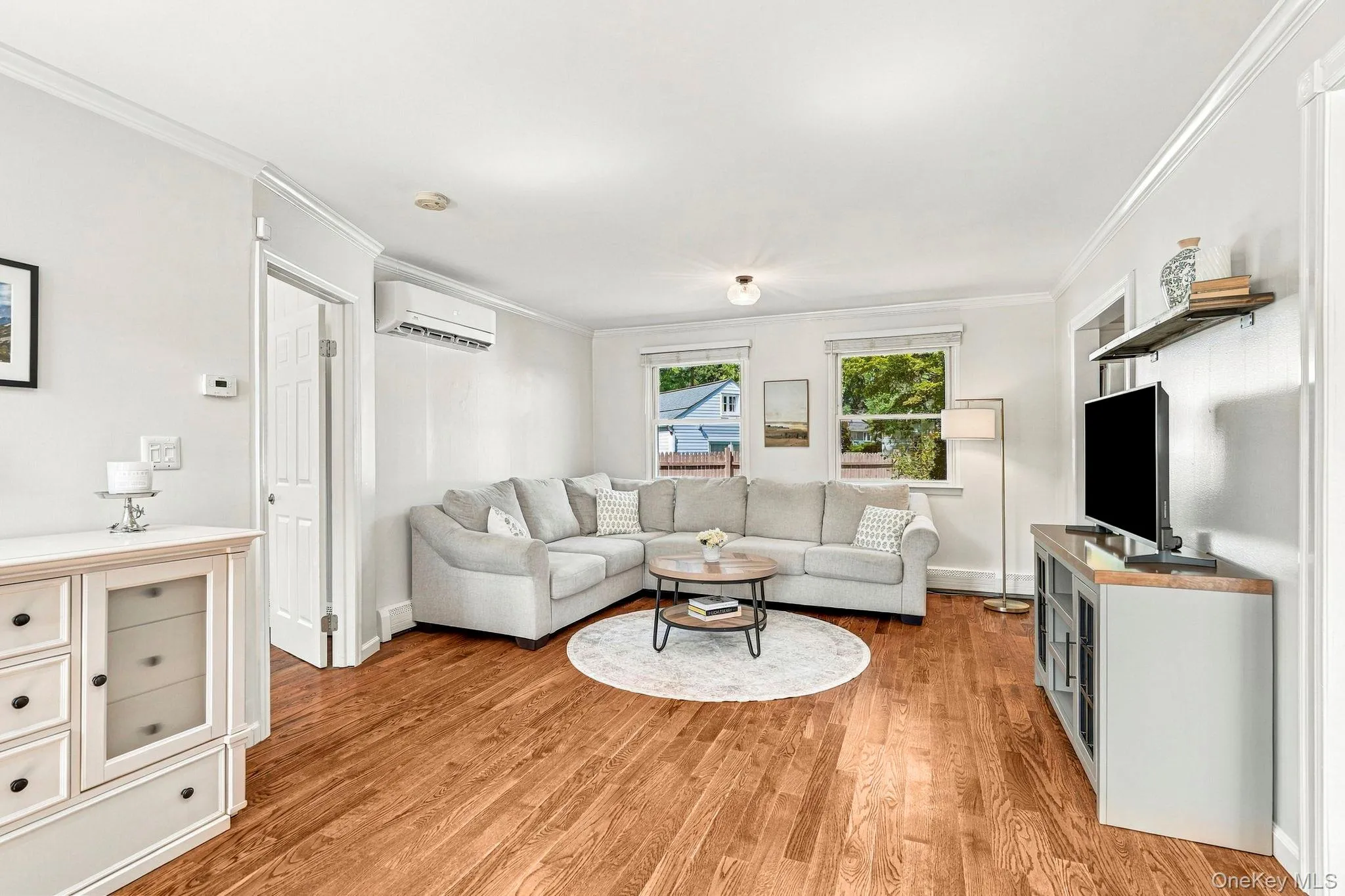 Hardwood flooring, white painted walls, white crown molding, recessed lighting, and wall-mounted air conditioning unit Hardwood flooring, white painted walls, white crown molding, recessed lighting, and wall-mounted air conditioning unit