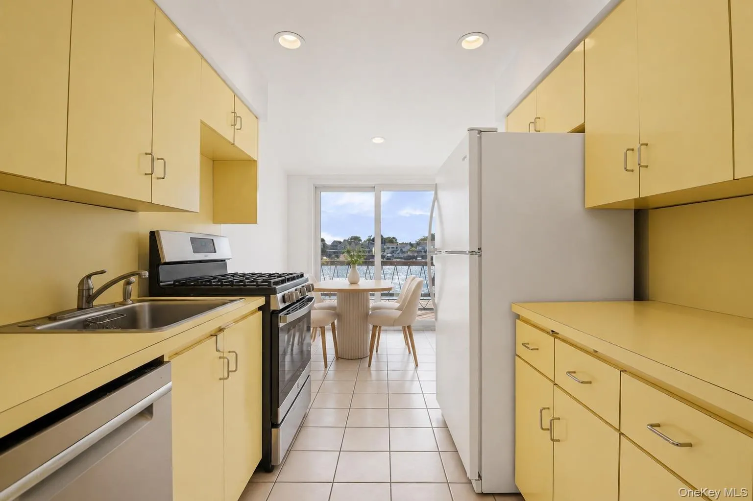 Galley kitchen featuring ample cabinetry, integrated stainless steel appliances, recessed lighting, and tile flooring Galley kitchen featuring ample cabinetry, integrated stainless steel appliances, recessed lighting, and tile flooring