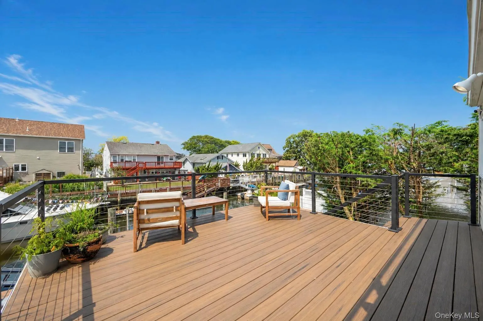 Expansive outdoor deck featuring composite decking, cable railing, and a waterside setting Expansive outdoor deck featuring composite decking, cable railing, and a waterside setting