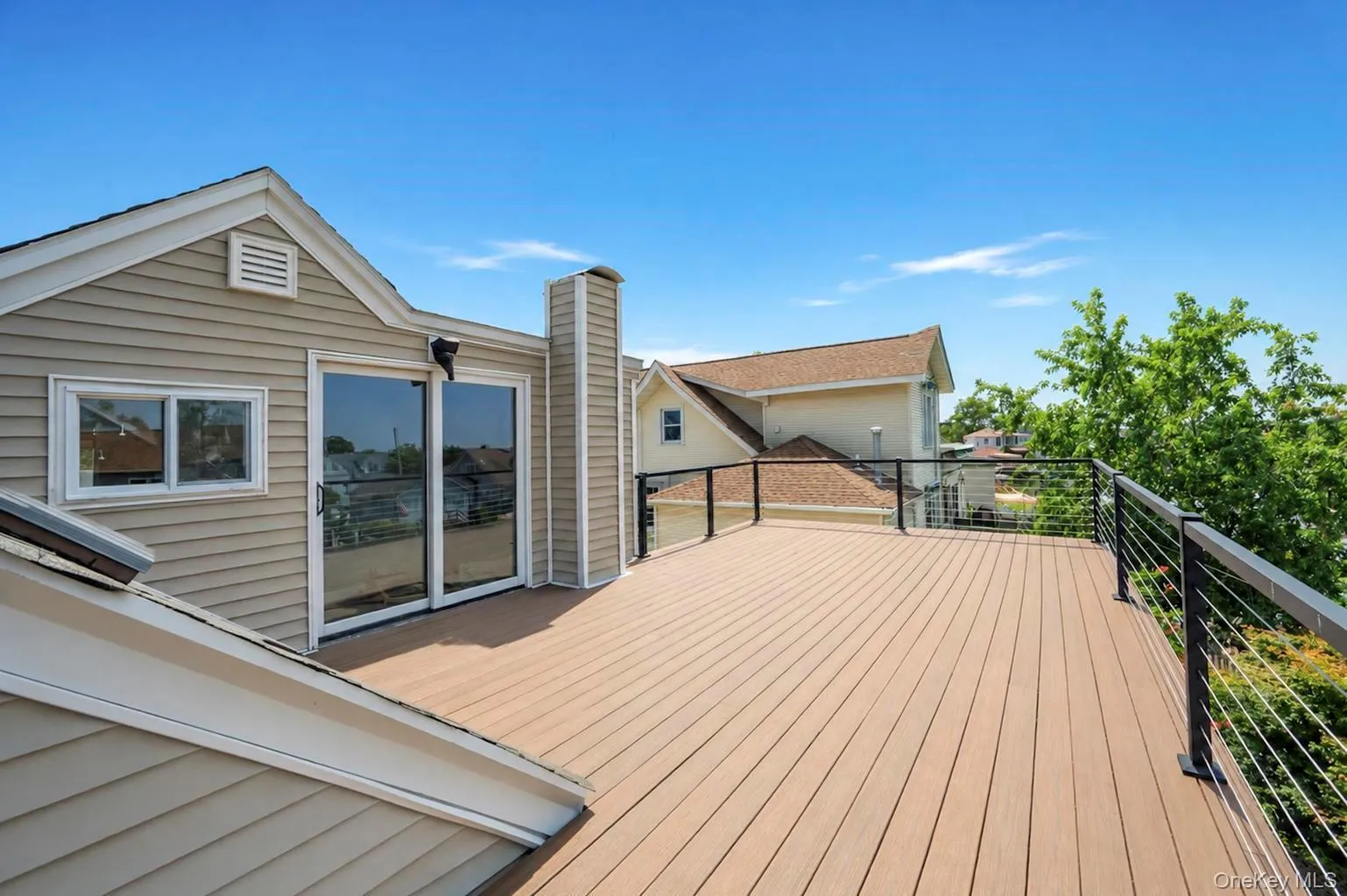 Expansive deck with composite decking, modern cable railings, and direct access through glass sliding doors Expansive deck with composite decking, modern cable railings, and direct access through glass sliding doors