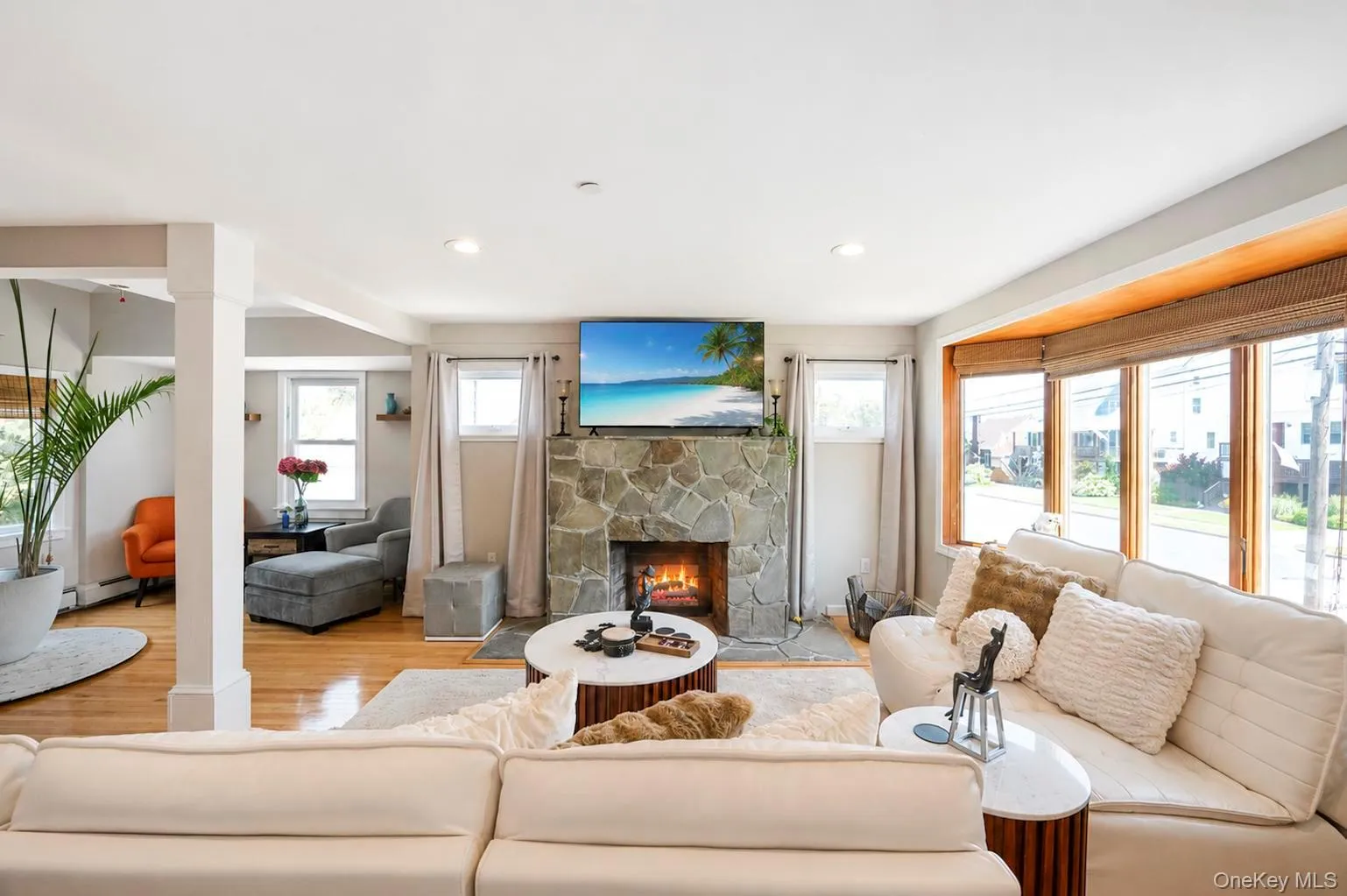 Hardwood flooring, stone-clad fireplace, recessed lighting, and a prominent bay window Hardwood flooring, stone-clad fireplace, recessed lighting, and a prominent bay window