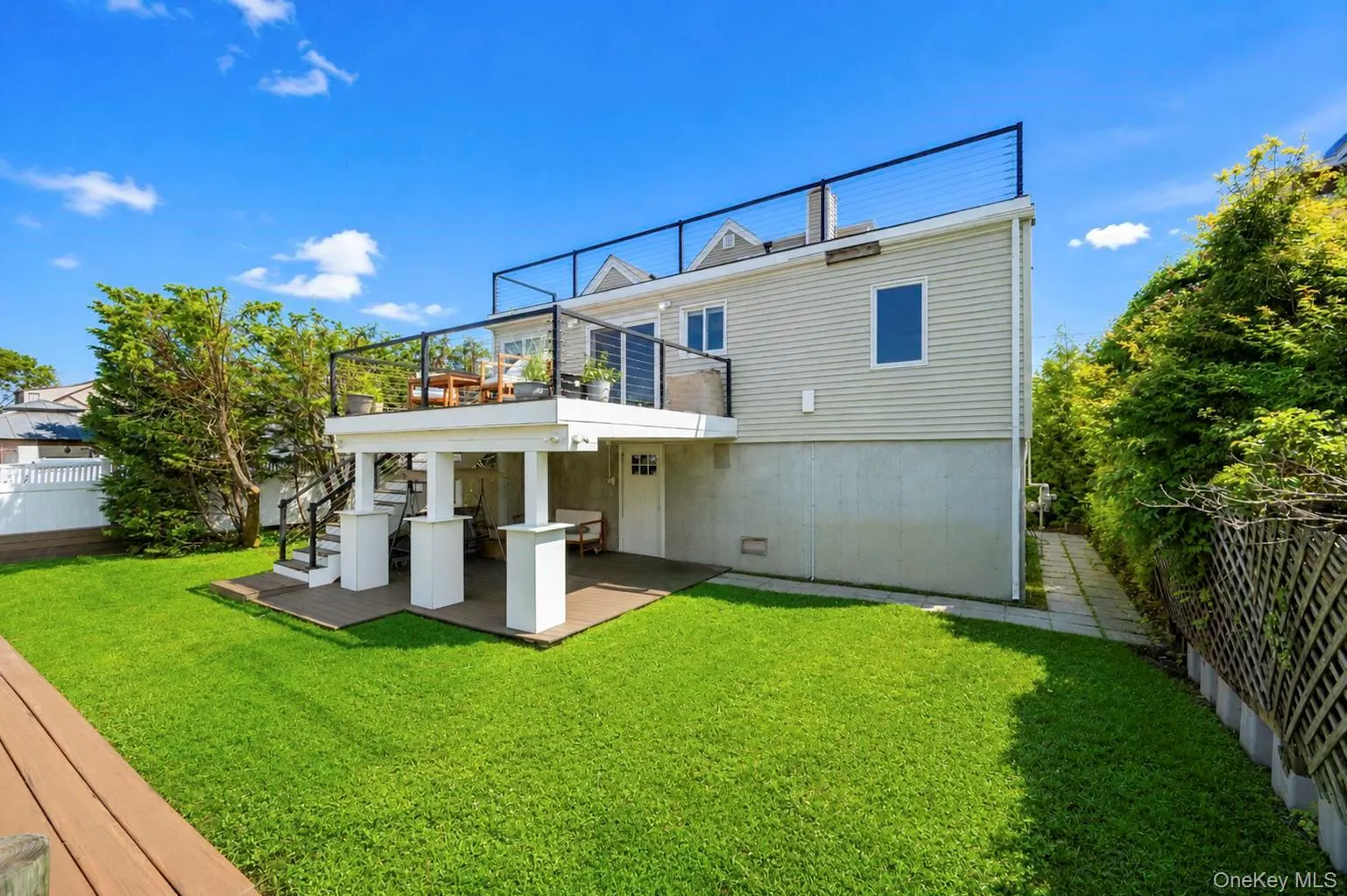 Expansive green lawn with a multi-level deck featuring a wire railing and staircase Expansive green lawn with a multi-level deck featuring a wire railing and staircase