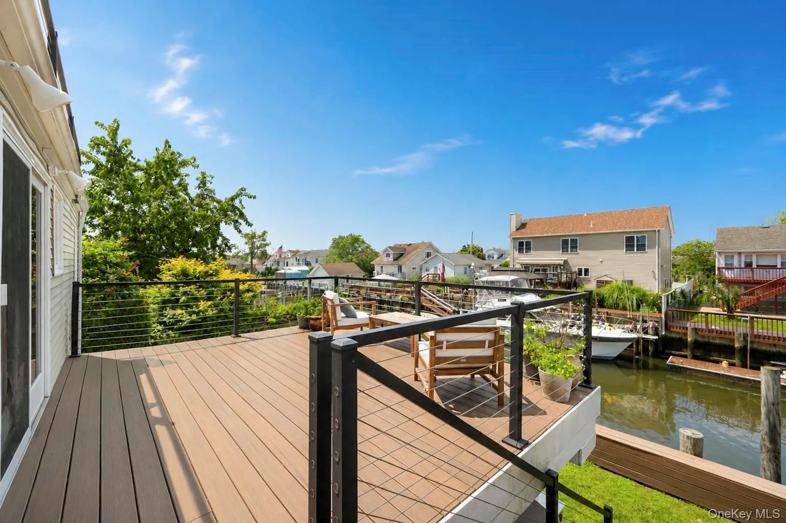Expansive outdoor deck featuring wood-finish flooring, black cable railing, and direct water access Expansive outdoor deck featuring wood-finish flooring, black cable railing, and direct water access