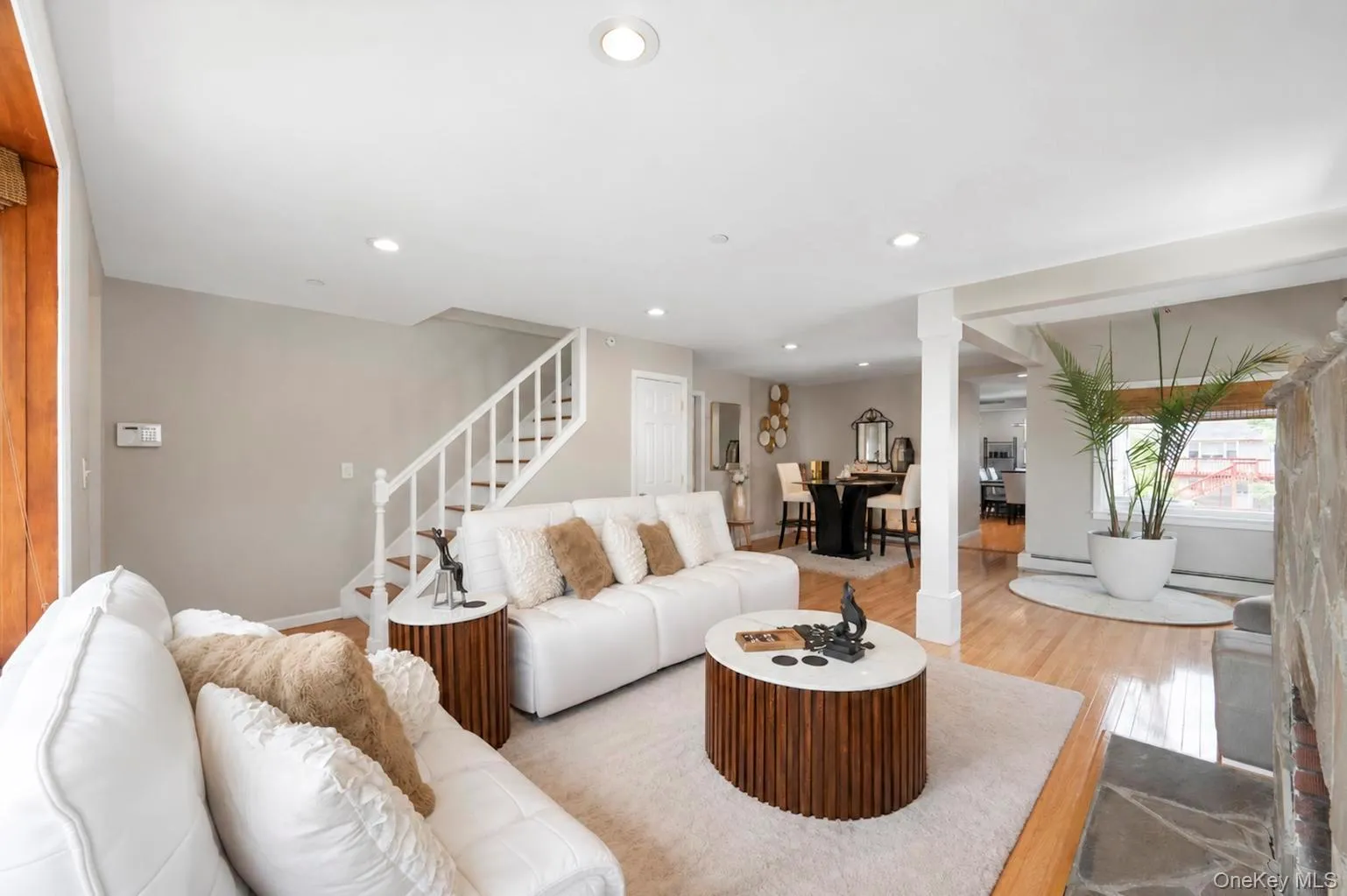 Recessed lighting illuminating hardwood-finish flooring, a white-painted staircase with wood treads, and a stone-clad fireplace Recessed lighting illuminating hardwood-finish flooring, a white-painted staircase with wood treads, and a stone-clad fireplace