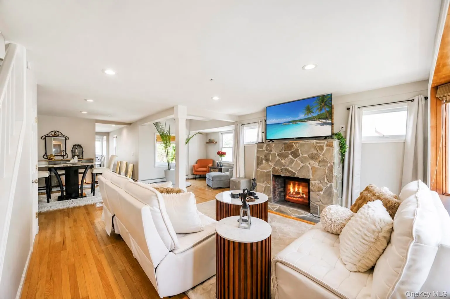 Stone-faced fireplace with a hearth, recessed lighting, hardwood flooring, and white painted walls Stone-faced fireplace with a hearth, recessed lighting, hardwood flooring, and white painted walls