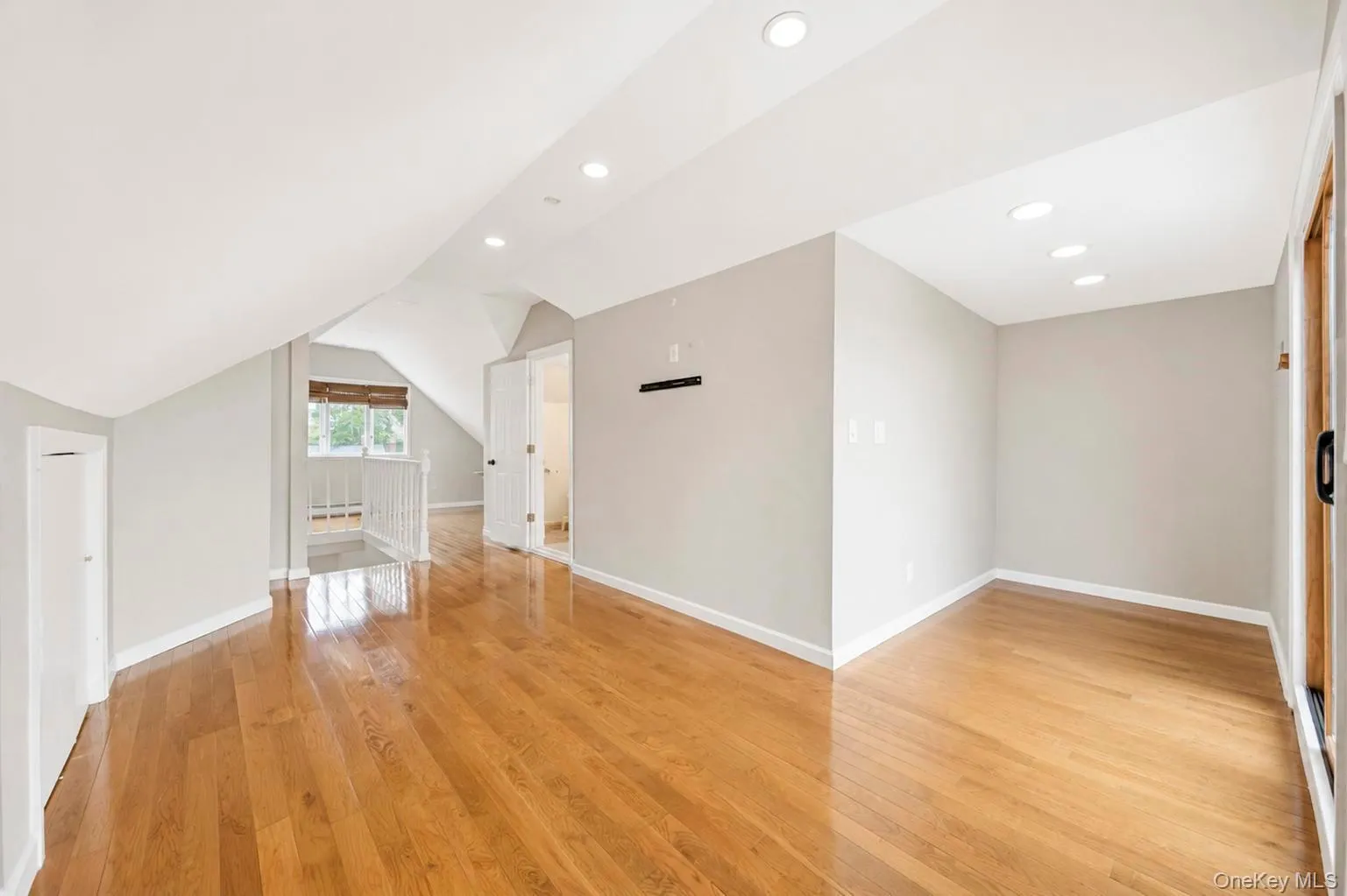 Hardwood flooring, recessed lighting, neutral wall tones, white trim, and a white balustrade Hardwood flooring, recessed lighting, neutral wall tones, white trim, and a white balustrade