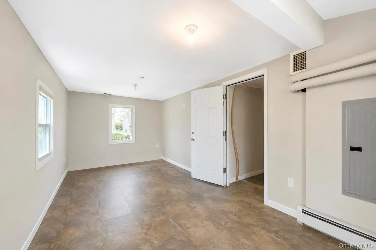 Spacious room featuring multiple windows, neutral wall tones, and durable tile flooring Spacious room featuring multiple windows, neutral wall tones, and durable tile flooring