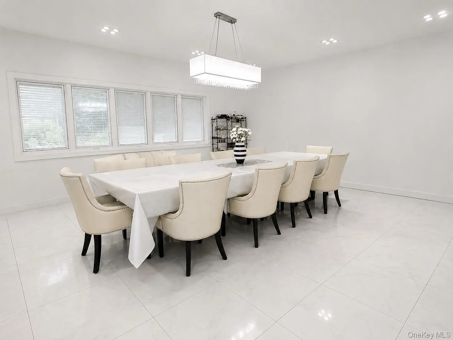 White tile flooring, recessed ceiling lighting, a contemporary rectangular chandelier, and a five-pane window White tile flooring, recessed ceiling lighting, a contemporary rectangular chandelier, and a five-pane window