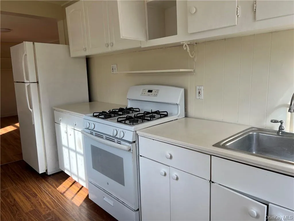 Kitchen featuring white cabinets, dark hardwood / wood-style flooring, sink, and white appliances Kitchen featuring white cabinets, dark hardwood / wood-style flooring, sink, and white appliances