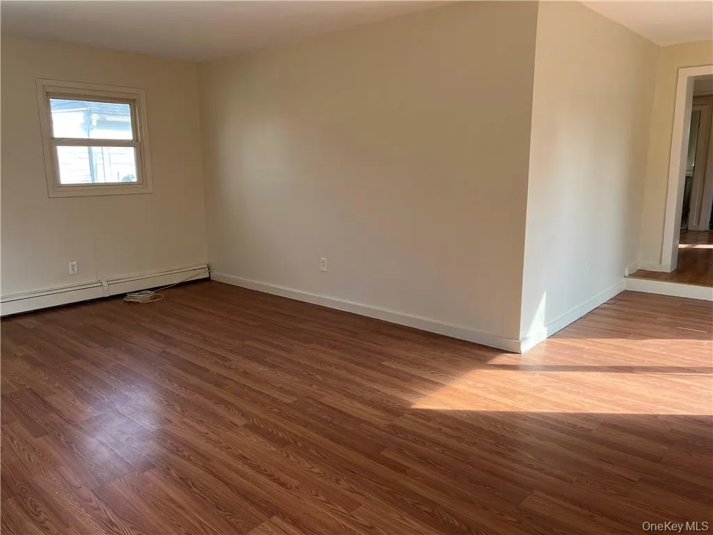 Living room with a baseboard radiator and dark hardwood / wood-style flooring Living room with a baseboard radiator and dark hardwood / wood-style flooring