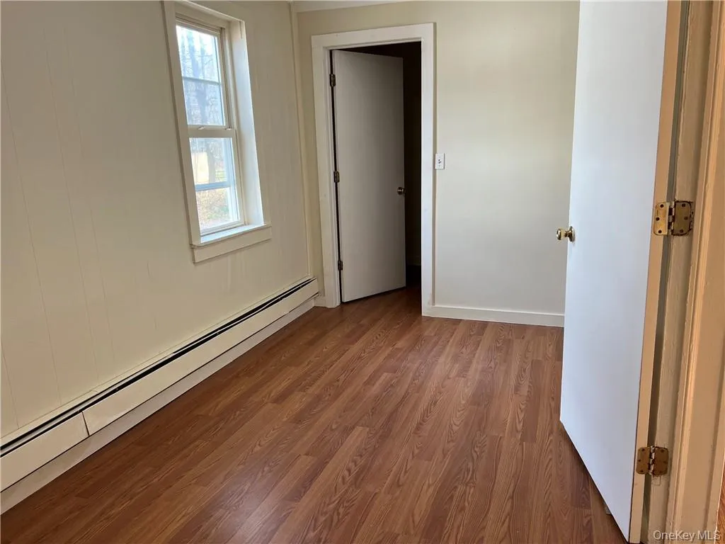 Bedroom #2 with baseboard heating and hardwood / wood-style flooring, and spacious closet. Bedroom #2 with baseboard heating and hardwood / wood-style flooring, and spacious closet.