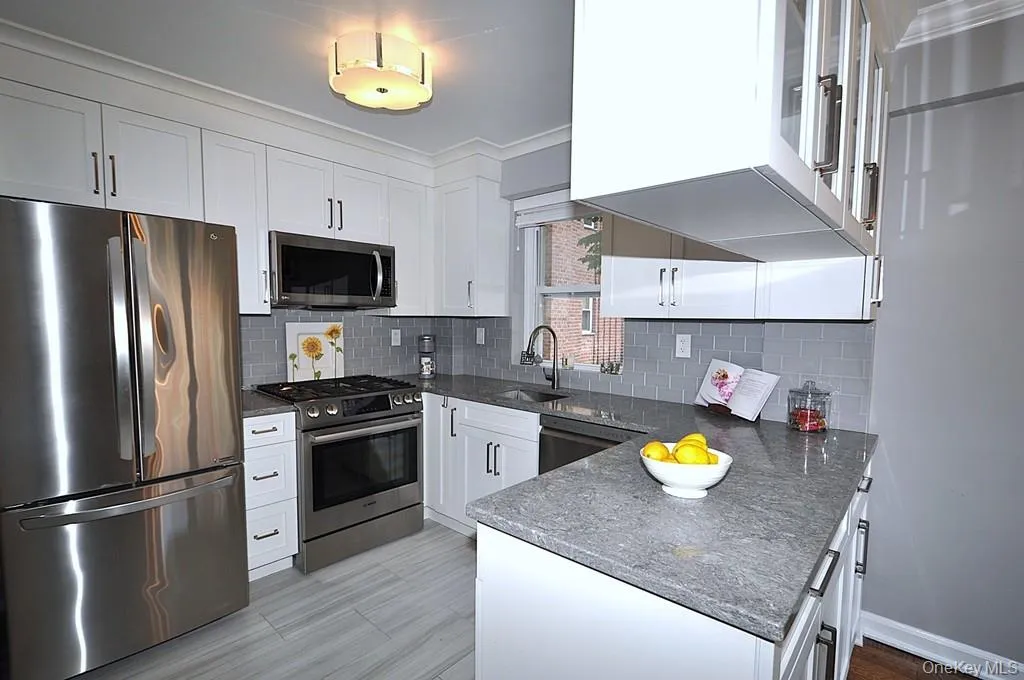 Professionally redesigned kitchen, where the dividing wall between the kitchen and dining room has been thoughtfully removed to create a sophisticated open-concept feel. Apeninsula with ample storage cabinetry subtly defines the kitchen while preserving the sense of openness and allowing natural light to flow. Quartz counters and stainless steel appliances. Professionally redesigned kitchen, where the dividing wall between the kitchen and dining room has been thoughtfully removed to create a sophisticated open-concept feel. Apeninsula with ample storage cabinetry subtly defines the kitchen while preserving the sense of openness and allowing natural light to flow. Quartz counters and stainless steel appliances.