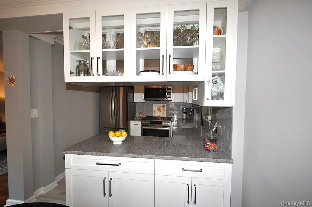 Professionally redesigned kitchen, where the dividing wall between the kitchen and dining room has been thoughtfully removed to create a sophisticated open-concept feel. Apeninsula with ample storage cabinetry subtly defines the kitchen while preserving the sense of openness and allowing natural light to flow. Quartz counters and stainless steel appliances. Professionally redesigned kitchen, where the dividing wall between the kitchen and dining room has been thoughtfully removed to create a sophisticated open-concept feel. Apeninsula with ample storage cabinetry subtly defines the kitchen while preserving the sense of openness and allowing natural light to flow. Quartz counters and stainless steel appliances.