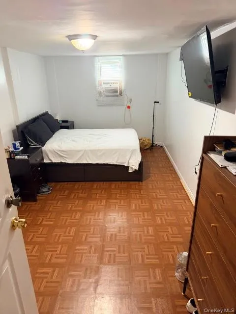 Wood-finish flooring, white walls, and a recessed window with an installed air conditioning unit Wood-finish flooring, white walls, and a recessed window with an installed air conditioning unit