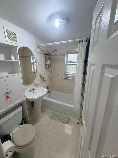 White pedestal sink, white bathtub, white toilet, white built-in storage cabinet, and tiled flooring White pedestal sink, white bathtub, white toilet, white built-in storage cabinet, and tiled flooring