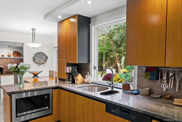 Wood-finish cabinetry paired with stone countertops and a stainless steel under-counter microwave Wood-finish cabinetry paired with stone countertops and a stainless steel under-counter microwave