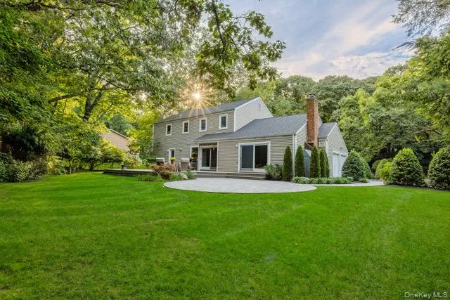 Spacious backyard featuring a manicured lawn, mature trees, a paver patio, and a brick chimney Spacious backyard featuring a manicured lawn, mature trees, a paver patio, and a brick chimney