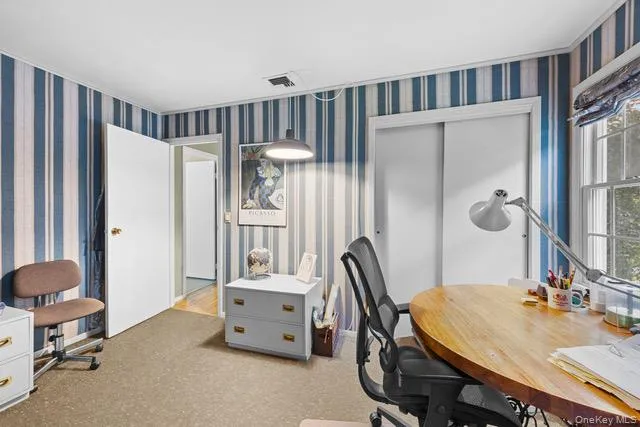 Room with striped wallpaper, a built-in sliding closet, a window with exterior views, and a recessed ceiling light fixture Room with striped wallpaper, a built-in sliding closet, a window with exterior views, and a recessed ceiling light fixture