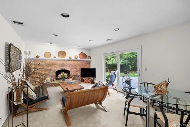 Exposed brick fireplace with hearth, recessed lighting, carpeted flooring, and sliding glass door Exposed brick fireplace with hearth, recessed lighting, carpeted flooring, and sliding glass door