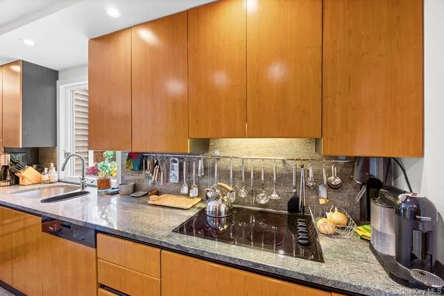 Wood-finish cabinetry paired with a built-in cooktop, undermount sink, and recessed lighting Wood-finish cabinetry paired with a built-in cooktop, undermount sink, and recessed lighting