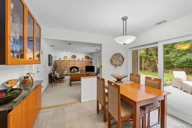 Kitchen and dining area looking into family room featuring tile flooring, glass-front cabinetry, and granite-finish countertops Kitchen and dining area looking into family room featuring tile flooring, glass-front cabinetry, and granite-finish countertops