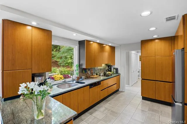 Sophisticated kitchen featuring warm wood-finish cabinetry with sleek black countertops, stainless steel appliances Sophisticated kitchen featuring warm wood-finish cabinetry with sleek black countertops, stainless steel appliances