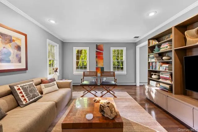 Sophisticated living room showcasing hardwood flooring, recessed ceiling lighting, and expansive windows framing natural light Sophisticated living room showcasing hardwood flooring, recessed ceiling lighting, and expansive windows framing natural light